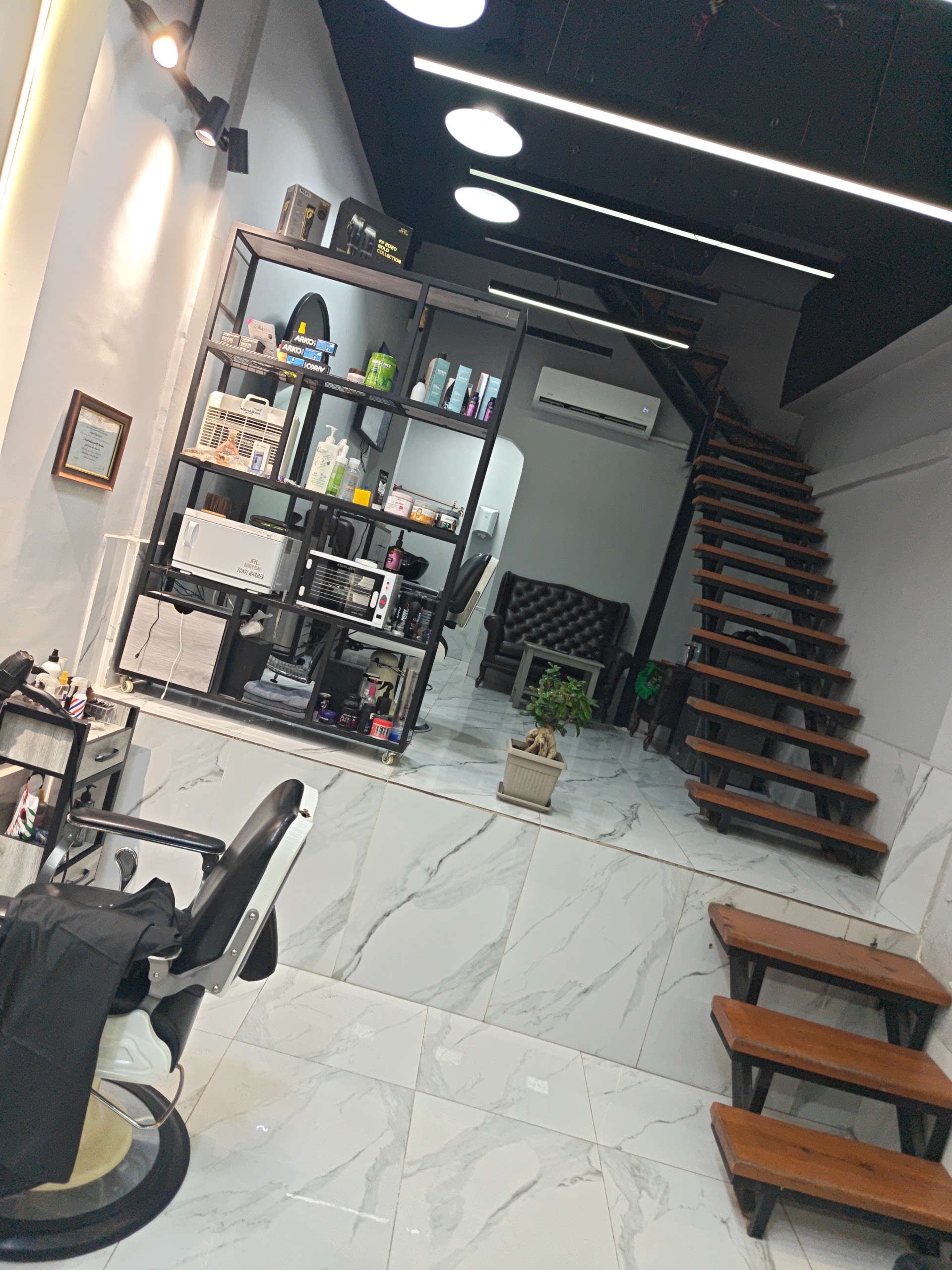 Styling tools, towel warmer and sterilizer shelved beside the barber chairs at Hamada Barber