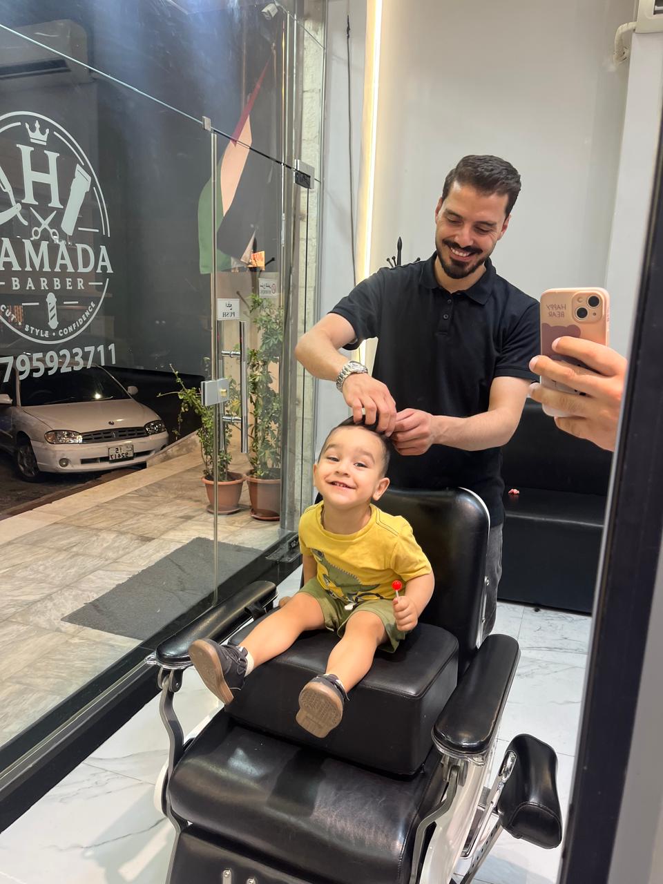 A client relaxed in the barber chair with the Hamada Barber logo reflected in the mirror